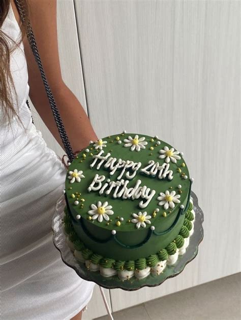 A Woman Holding A Green Birthday Cake With Daisies On It