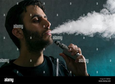 young man vape electronic cigarette cloud by using a mod, smoke tricks of vaping device ...