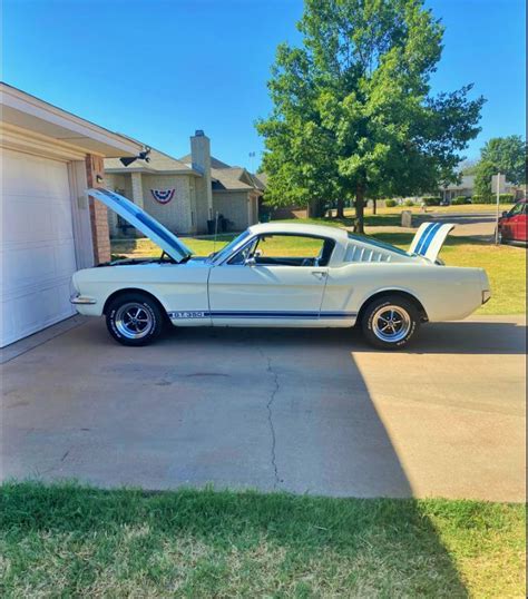 A White Mustang Parked In Front Of A Garage