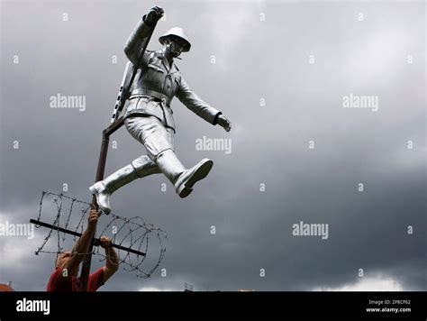 A Worker Seen Placing The Sculpture Of East German Border Guard