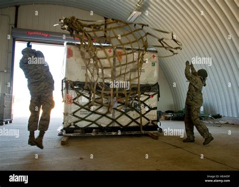 U.S. Air Force airmen toss a pallet net over cargo so they can secure it for air transportation ...