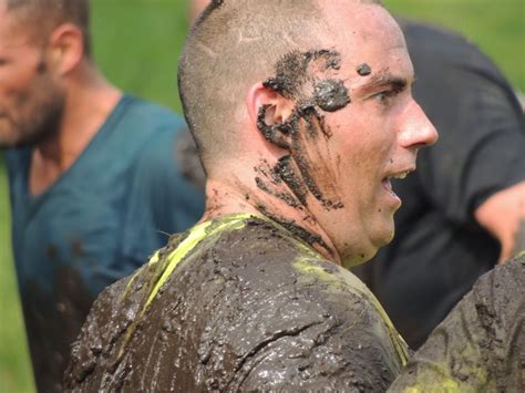 A Man With Mud All Over His Face And Neck Standing In Front Of Other Men