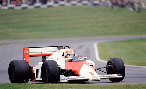 A Man Driving A Race Car On A Track With People Watching From The Sidelines