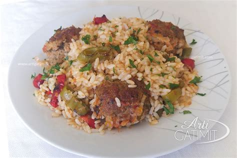 A White Plate Topped With Rice And Meatballs Covered In Green Onions