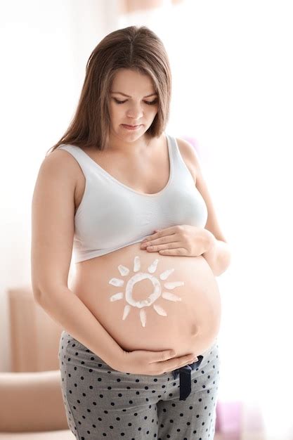 Mulher grávida sol pintado na barriga contra fundo desfocado Foto