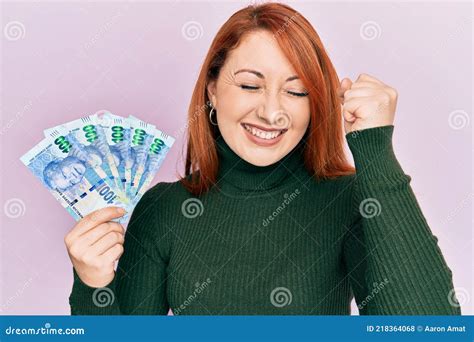 Beautiful Redhead Woman Holding South African 100 Rand Banknotes Screaming Proud Celebrating