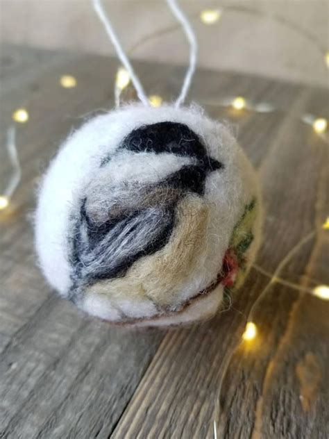 A Wool Ball Ornament Hanging On A String With Lights In The Back Ground