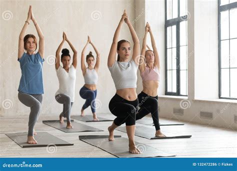 Group Of Young People Practicing Yoga Lesson Warrior One Pose Stock