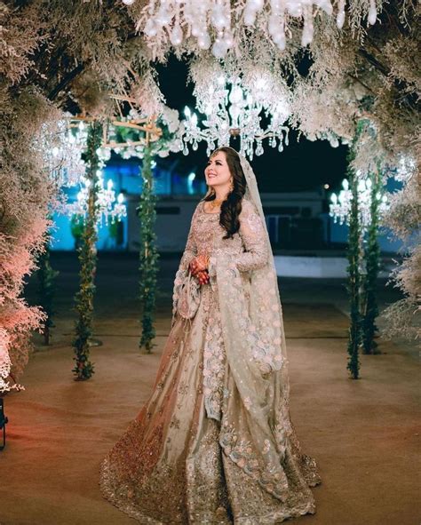 A Woman In A Wedding Dress Standing Under An Archway With Chandelier