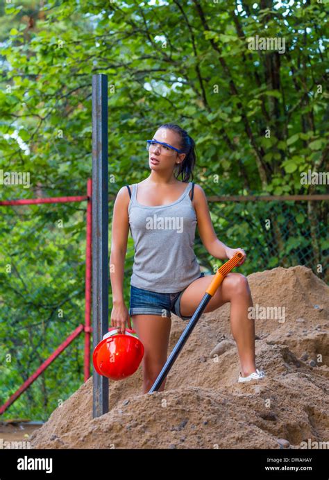 Pretty young woman builder digging a shovel Stock Photo - Alamy