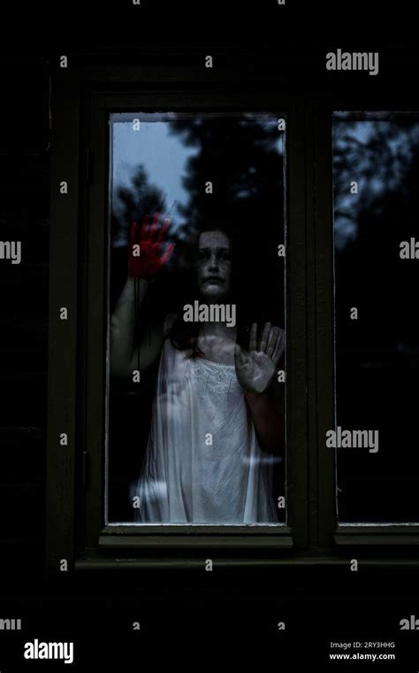 Female Ghost With Blood On Hand Seen Through Glass Window Of Haunted