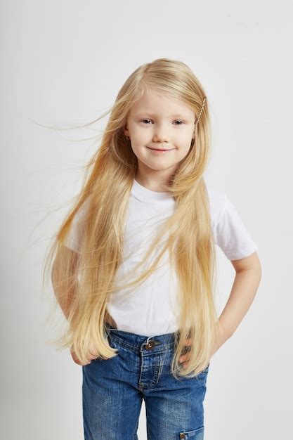 Menina Longos Cabelos Loiros E Jeans Posando Em Uma Parede Branca