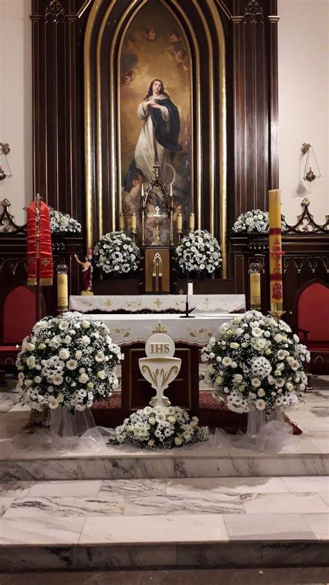 The Altar Is Decorated With White Flowers And Greenery In Front Of An