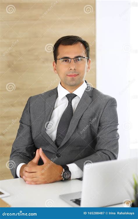 Cheerful Smiling Businessman Sitting At A Desk In Modern Office