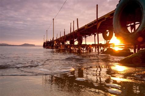 Premium Photo | Pier on the beach at sunset