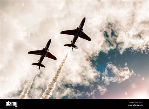 Two Fighter Jets Fly In The Cloudy Sky Line Of Exhaust Behind Them