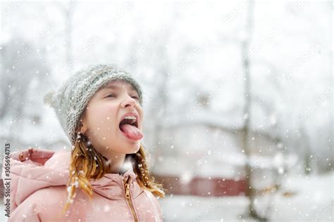 Adorable Young Girl Catching Snowflakes With Her Tongue In Beautiful