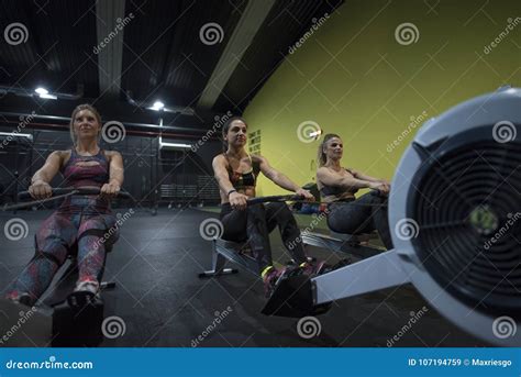 Women Training Rowing In Gym With Exercises Machines And Pull Rope