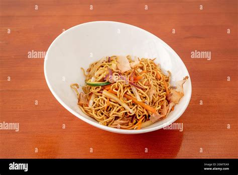 White Bowl Of Sauteed Noodles With Fresh Vegetables And Yakisoba Sauce