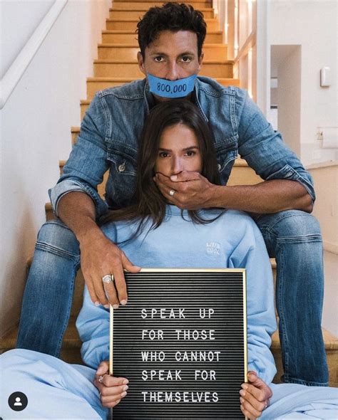 A Man And Woman Sitting On Top Of Each Other Holding A Sign That Says