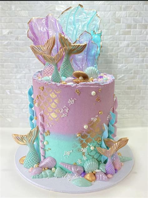 There Is A Cake Decorated With Mermaids And Seashells