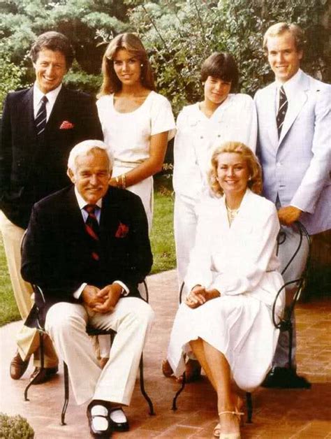 A Group Of People Posing For A Photo In Front Of Some Bushes And Trees