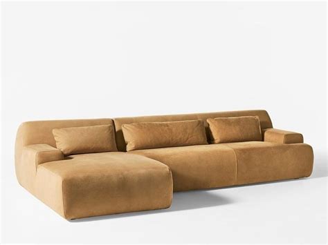 A Brown Couch With Pillows On It In Front Of A White Wall