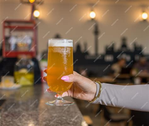 Premium Photo Womans Hand Holding Glass Of Beer Up High In Restaurant