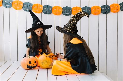 Free Photo | Two pretty halloween witches painting pumpkins