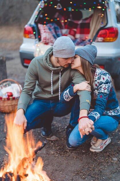 Premium Photo Smiling Couple Embracing While Sitting By Trunk