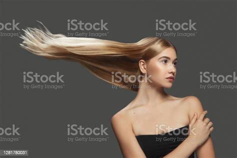 Beautiful Model With Long Smooth Flying Blonde Hair Isolated On Dark