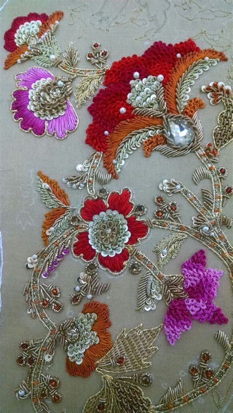 An Embroidered Table Cloth With Flowers And Leaves In Red Pink Orange