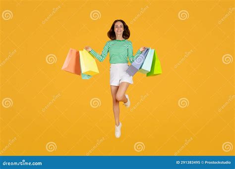 Excited Pretty Young Lady Jumping In Air With Purchases Stock Image