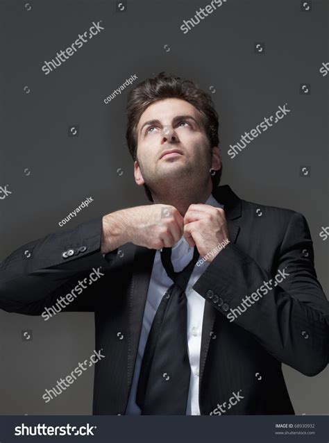 Businessman In Suit Loosening Up His Tie Isolated On Gray Stock Photo