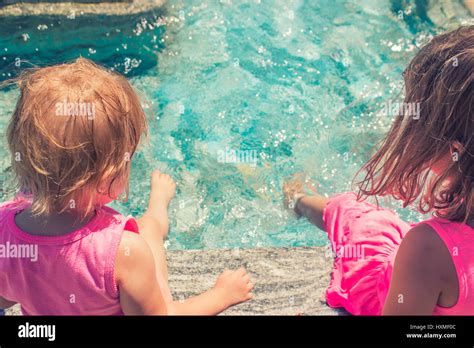 Zwei Kleine Mädchen Sitzen Am Rand Des Pools Spritzwasser Stockfotografie Alamy