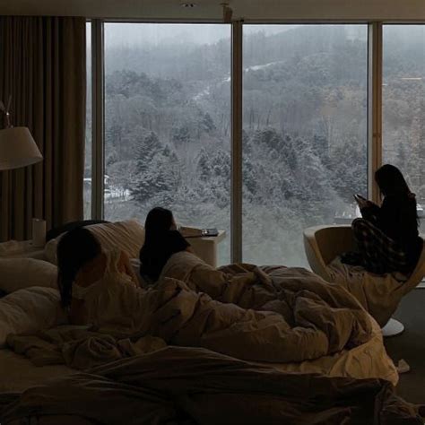 Two People Laying In Bed Looking Out The Window At Snow Covered Trees