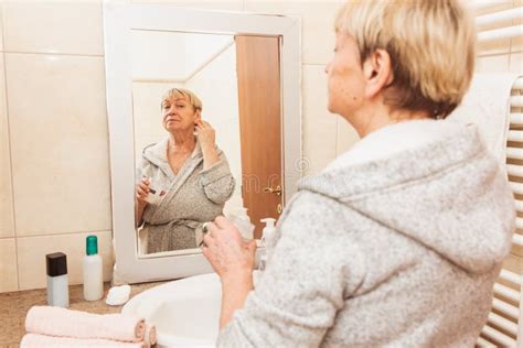 Senior Woman Touching Her Soft Face Skin And Does Massage Looking In