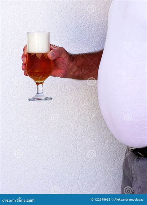 Man With Beer Belly Holding A Glass Full Of Beer And Beer Foam Stock