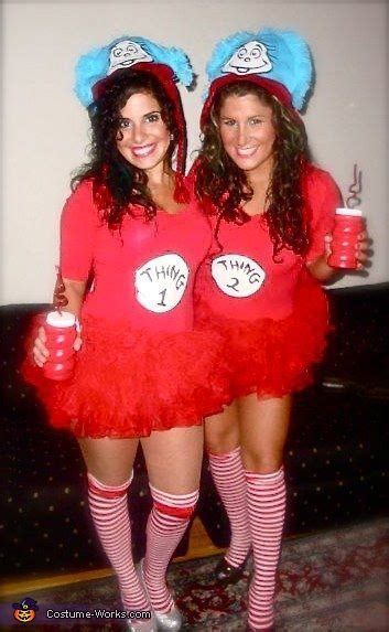 Two Women Dressed In Costumes Posing For The Camera With One Holding A Drink And Another Wearing