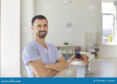 Smiling Masseur Or Physiotherapist Standing Arms Folded In Massage Room