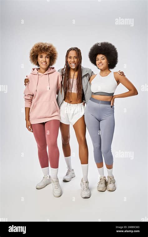 Joyful African American Women In Sportswear Standing Together On Grey