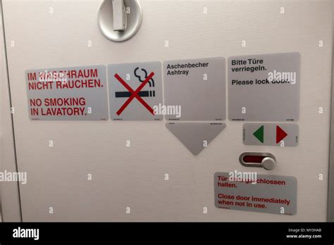 Airplane Toilet Door With No Smoking Warning Signs Beside An Ashtray