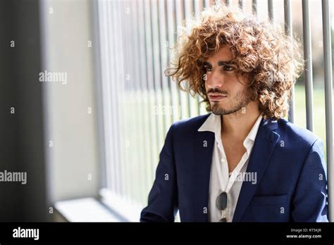 Portrait of young fashionable man with beard and curly hair Stock Photo ...