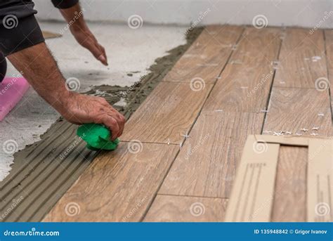 Worker Placing Ceramic Floor Tiles On Adhesive Surface Leveling With