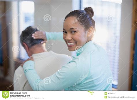 Rear View Of Portrait Of Smiling Female Therapist Giving Neck Massaging