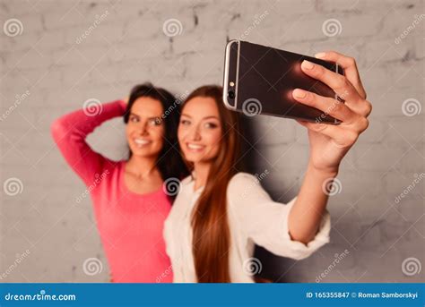 Two Girlfriends Make Selfie Photos On A Mobile Phone Stock Image