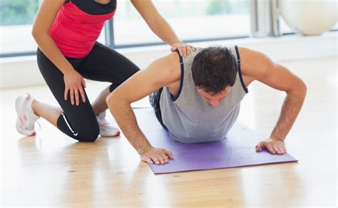 Premium Photo Female Trainer Assisting Man With Push Ups In Gym