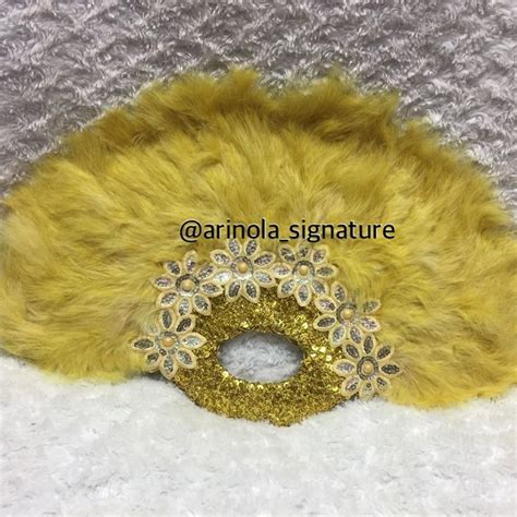 A Close Up Of A Yellow Fur Mask On A White Surface With Gold Sequins