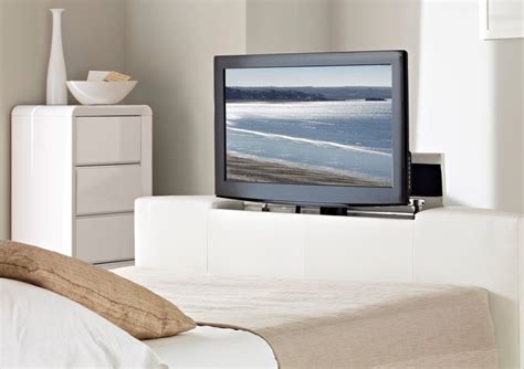 A Flat Screen Tv Sitting On Top Of A White Dresser Next To A Bed In A