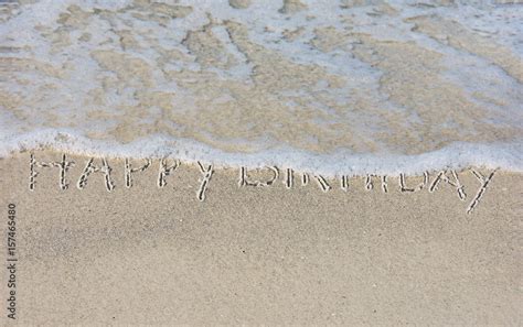 Happy Birthday Written In Beach Sand With Frothy Ocean Water Stock